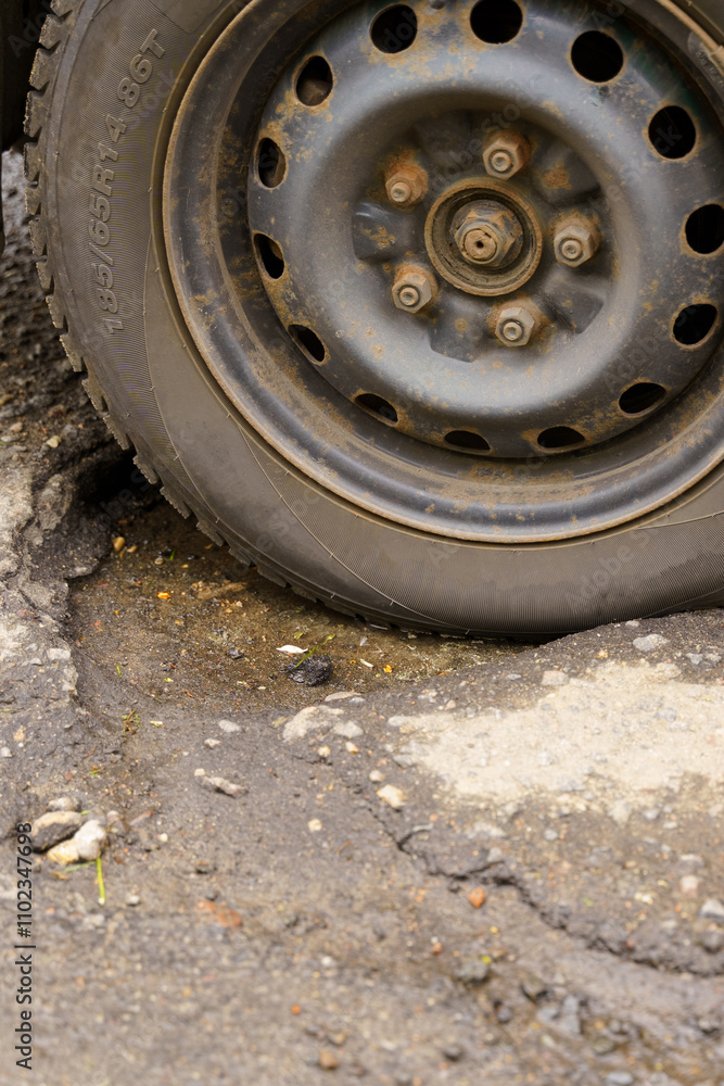 A tire trapped in a pothole on an uneven road during overcast weather A tire trapped in a pothole on an uneven road during overcast weather