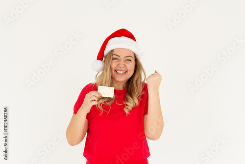 Excited happy positive cheerful smiling Beautiful woman wearing christmas hat hold credit card raise fist in victory