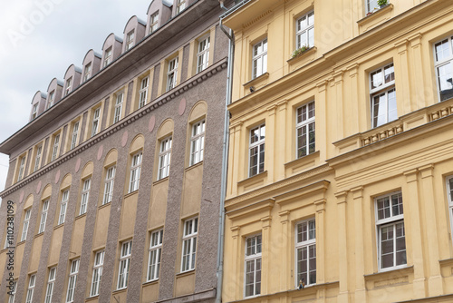 Next to a smaller structure, there stands a large building that features numerous windows, creating an interesting architectural contrast