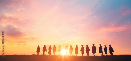 Silhouetted graduates stand at sunset, celebrating achievement and future.