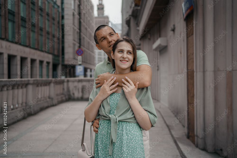 Naklejka premium Happy couple of tourists walking embraced while sightseeing the town. Happy couple in front of palace of culture and science in Warsaw, Poland. Close up of a couple kissing.