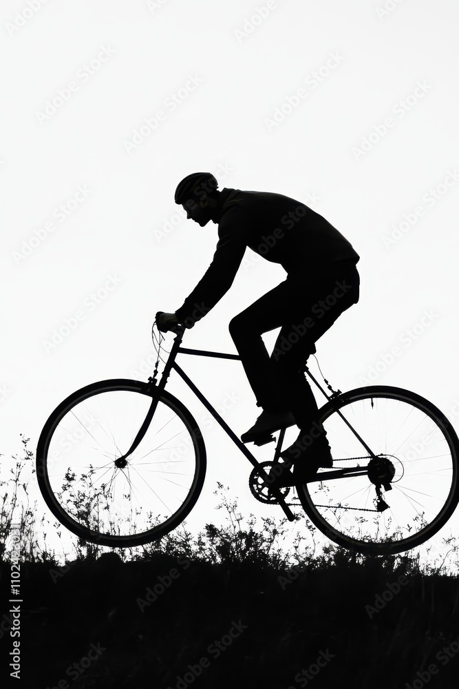 Silhouette of a male cyclist in motion, capturing an adventurous spirit against a stark white background. Silhouette of a male cyclist in motion, capturing an adventurous spirit against a stark white background.