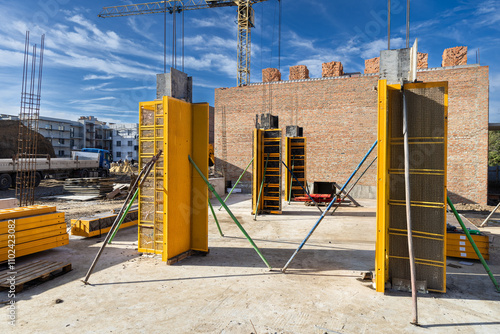 Construction site with yellow formwork, cranes, and materials under a bright blue sky photo