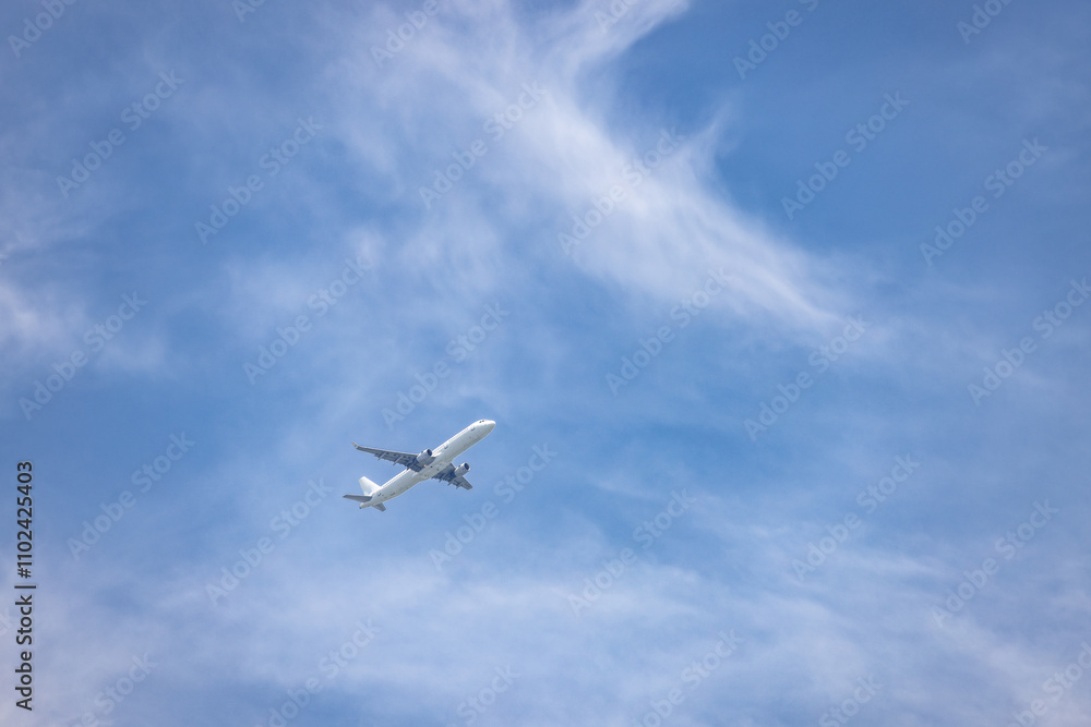 Obraz premium A striking view of a commercial airplane soaring through a vibrant blue sky with delicate, wispy clouds. This image represents the beauty of aviation and the limitless possibilities of global travel 
