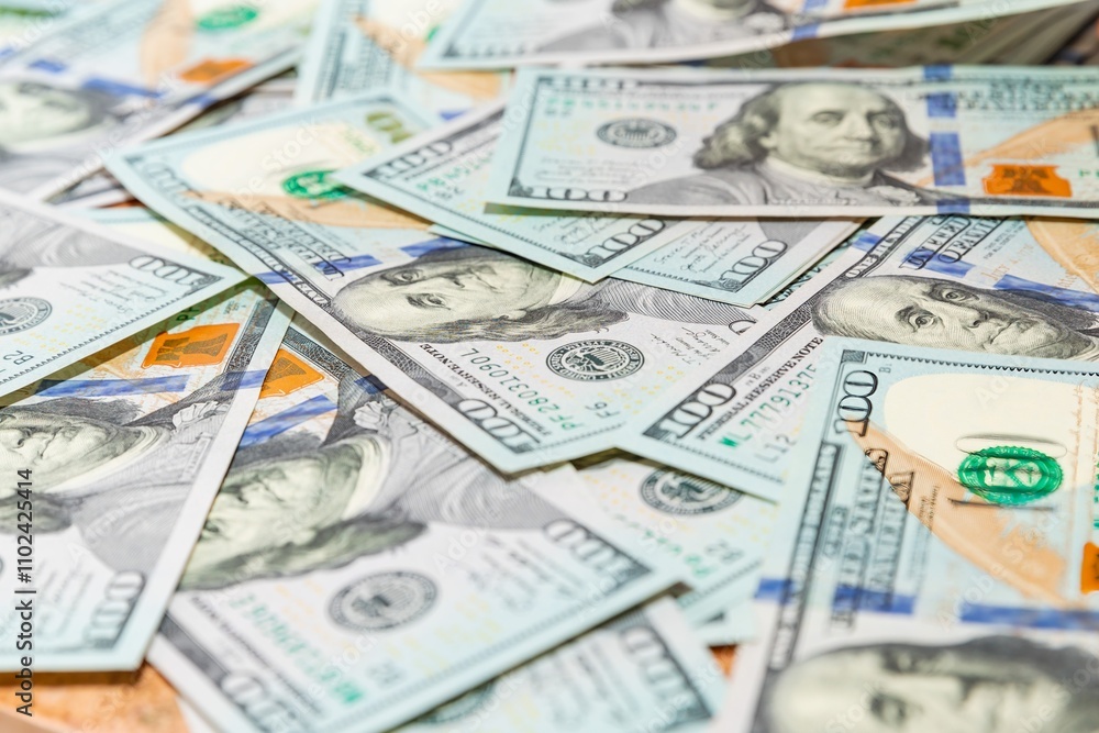 Scattered hundred-dollar bills in a close-up view on a wooden table Scattered hundred-dollar bills in a close-up view on a wooden table