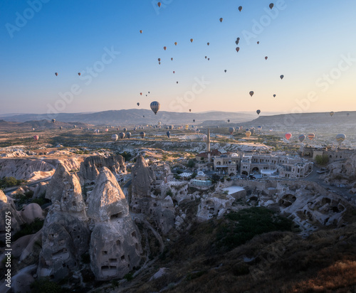 panorama sulle tipiche formazioni rocciose della cappadocia con le mongolfiere che le attraversano all'alba photo