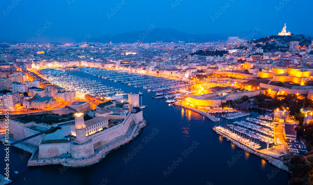 Fototapeta premium Aerial view of old port, Tour du Fanal and Basilica of Notre Dame at Marseille, France at night