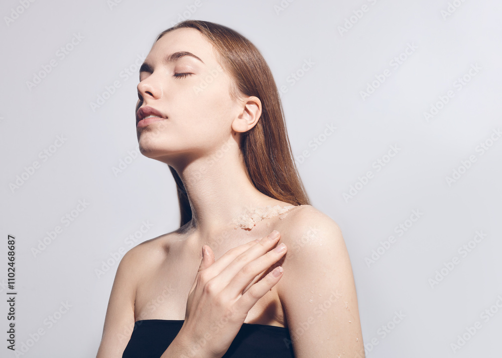 A beautiful brunette uses a scrub applying it to her body