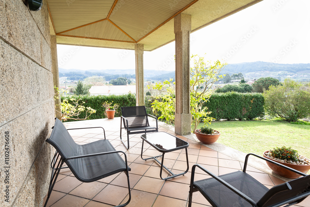 Obraz premium Terrace with porch in a country house, metal and black terrace table and chairs