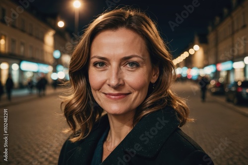 Close portrait of a smiling 40s Polish woman looking at the camera, Polish city outdoors at night blurred background