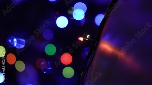 close-up shot of the lights of the garland, flashing quickly on the New Year tree, multi-colored lanterns behind