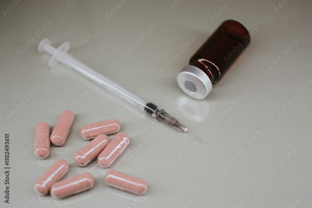 A syringe with a thin sharp needle, an injection ampoule and multi-colored pills A syringe with a thin sharp needle, an injection ampoule and multi-colored pills