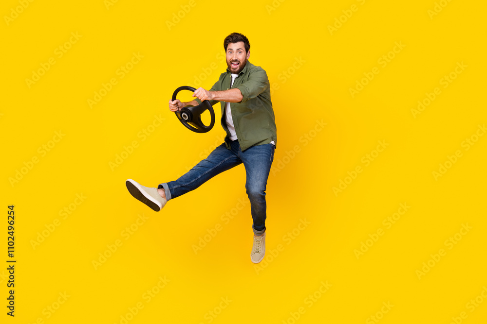 Full size photo of nice young man jump hold wheel wear shirt isolated on yellow color background Full size photo of nice young man jump hold wheel wear shirt isolated on yellow color background