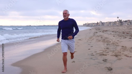 A mature 66 year old man jogging at the beach in Southern California. Slow Motion.