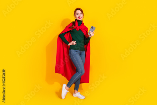 Full length photo of cheerful pretty lady dressed green jumper red mantle texting modern device empty space isolated yellow color background