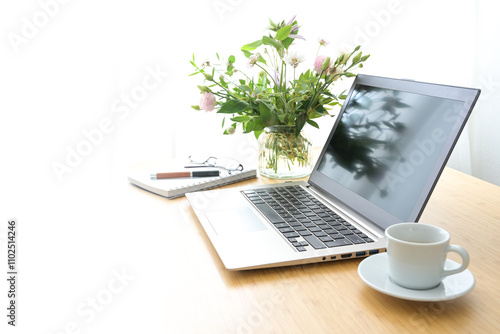 Bright feminine workspace with laptop, coffee and flowers on a wooden table in a cozy home office, background fades to white, concept for business, study or creative work, copy space