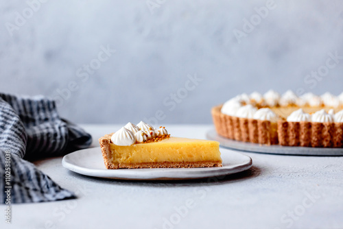 Lemon tart on a plaster surface with piped whipped cream-7 photo