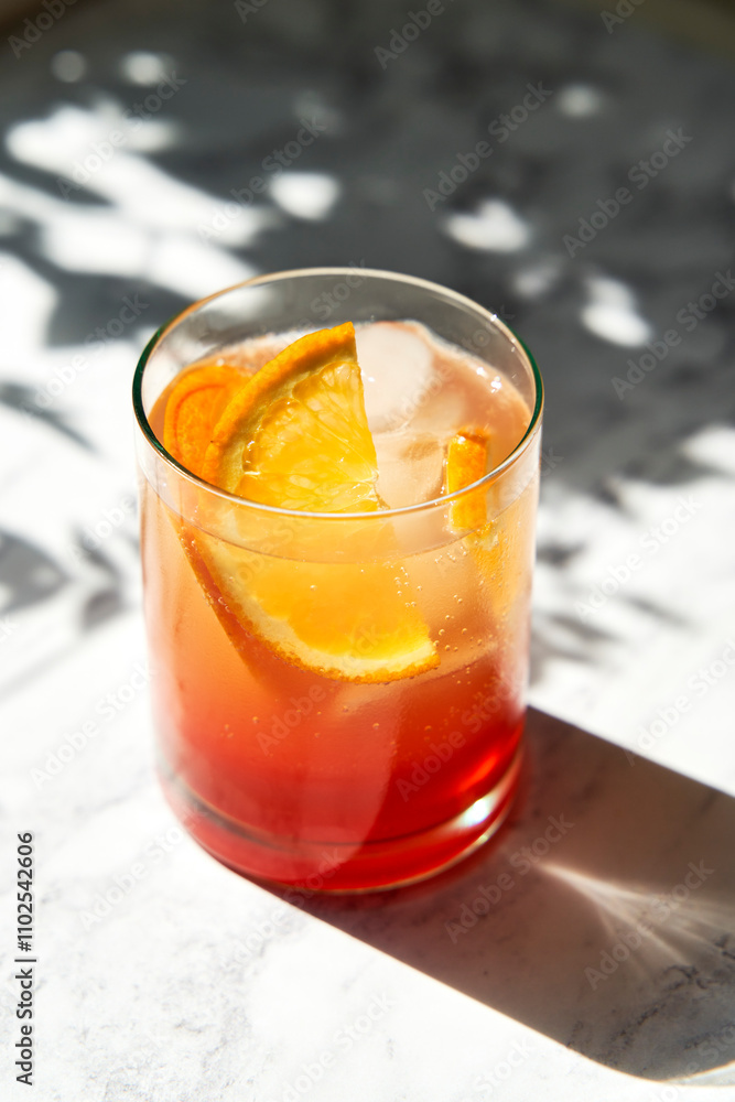 Aperol Spritz on Marble Surface with shadow and hard sunlight, with orange slice garnish Aperol Spritz on Marble Surface with shadow and hard sunlight, with orange slice garnish