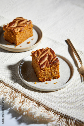 Pumpkin Cake Square with swirls of almond butter on a neutral background with gold forks photo