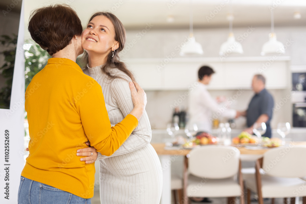 Happy mother meets her daughter, hugs and kisses her. In the background father shakes the guy hand Happy mother meets her daughter, hugs and kisses her. In the background father shakes the guy hand