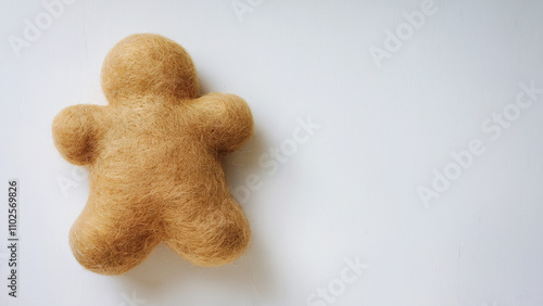 A fluffy, golden gingerbread man, crafted using needle felting technique and has soft and rounded shape, fastive background. photo