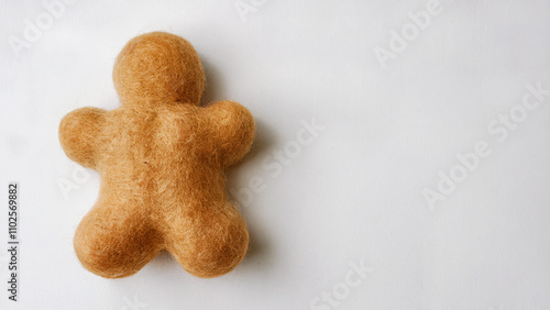 A fluffy, golden gingerbread man, crafted using needle felting technique and has soft and rounded shape, fastive background. photo