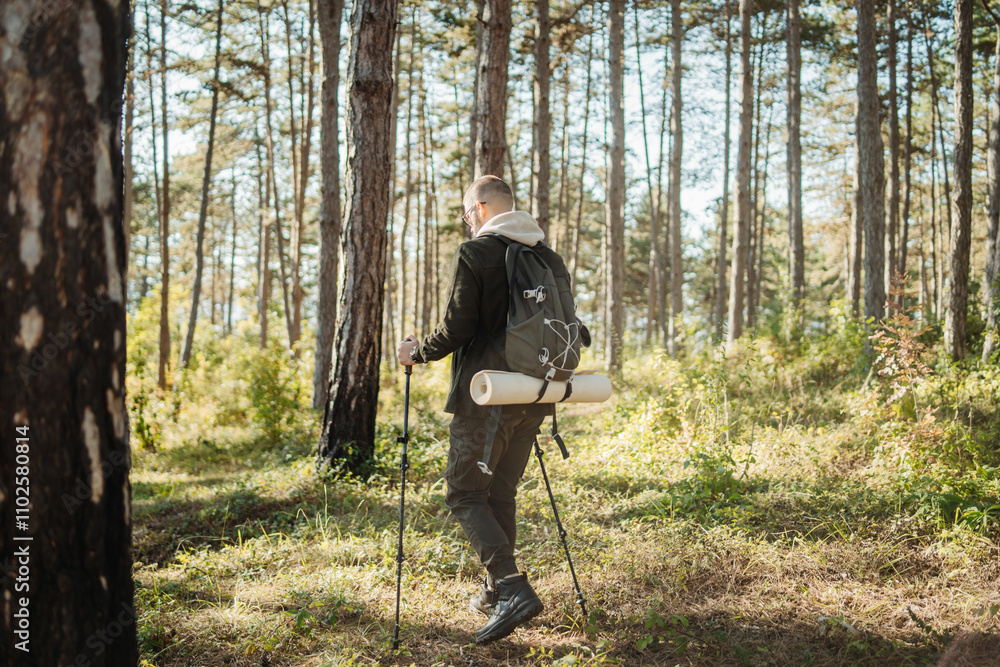 Fototapeta premium Young caucasian man hiking or trekking through the forest 