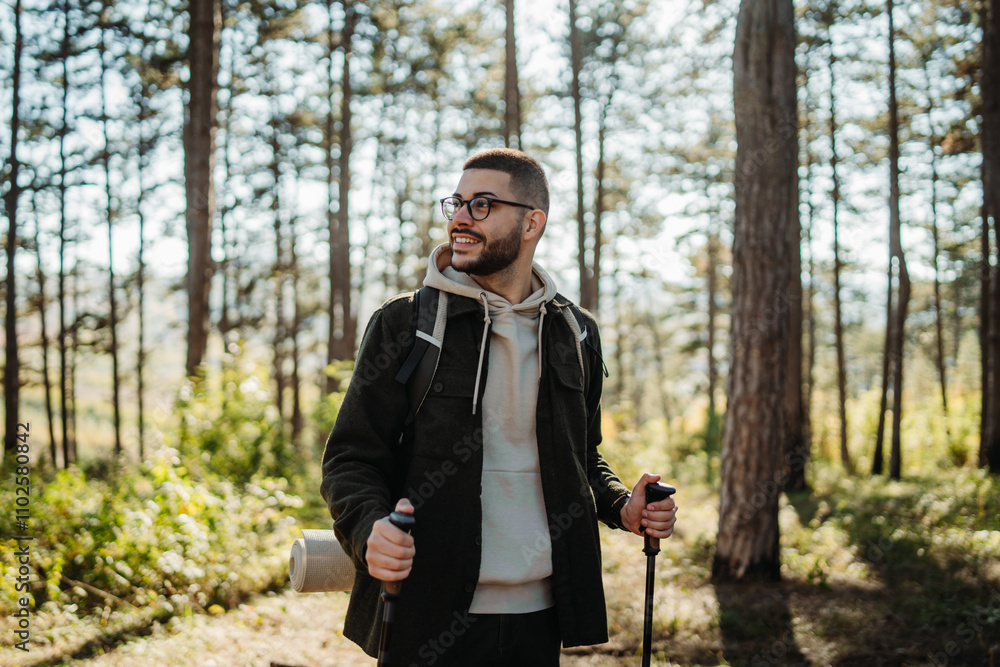 Young caucasian man hiking or trekking through the forest Young caucasian man hiking or trekking through the forest