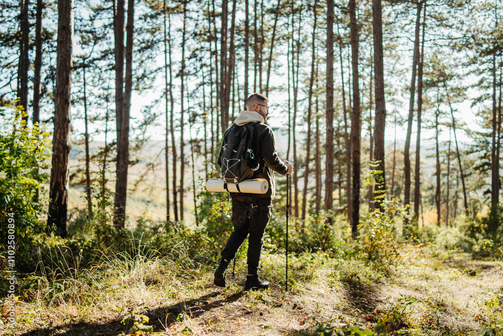 Young caucasian man hiking or trekking through the forest Young caucasian man hiking or trekking through the forest