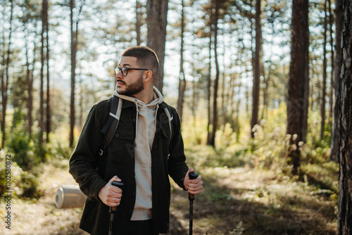 Young caucasian man hiking or trekking through the forest 