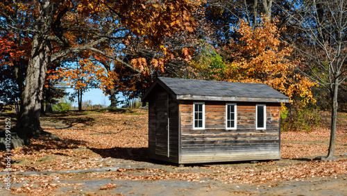 small weathered cabin surrounded by fall trees in a park setting. photo