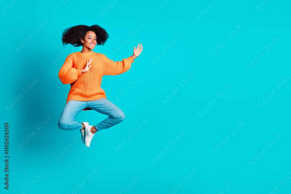 Full size photo of pretty young girl jump fighting wear trendy knitwear orange outfit isolated on aquamarine color background Full size photo of pretty young girl jump fighting wear trendy knitwear orange outfit isolated on aquamarine color background