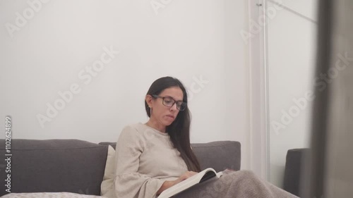 young latin woman reading a book on her bed, in her spare time