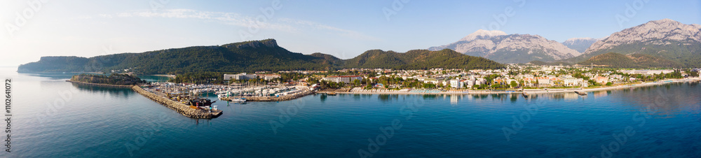 Scenic panoramic summer view of Kemer on Mediterranean coast at foot of Taurus Mountains overlooking residential buildings and marina. Famous tourist city and beach resort on Turkish Riviera Scenic panoramic summer view of Kemer on Mediterranean coast at foot of Taurus Mountains overlooking residential buildings and marina. Famous tourist city and beach resort on Turkish Riviera
