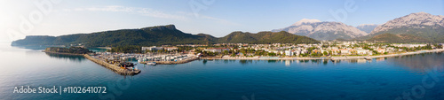 Scenic panoramic summer view of Kemer on Mediterranean coast at foot of Taurus Mountains overlooking residential buildings and marina. Famous tourist city and beach resort on Turkish Riviera