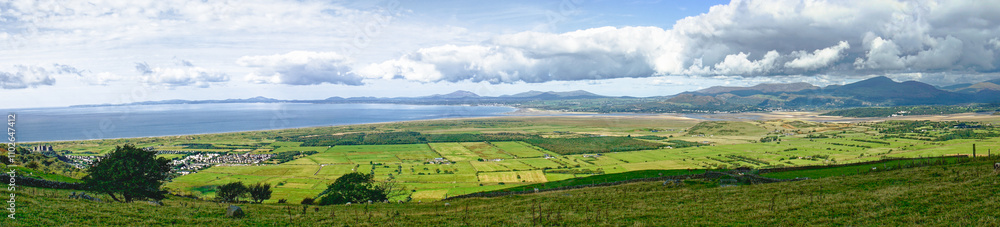 Panorama west over farmland and Ceredigion Bay. Harlech Castle extreme left, Snowdownia Mountains right, Llyn Peninsula on left horizon. West Wales Panorama west over farmland and Ceredigion Bay. Harlech Castle extreme left, Snowdownia Mountains right, Llyn Peninsula on left horizon. West Wales