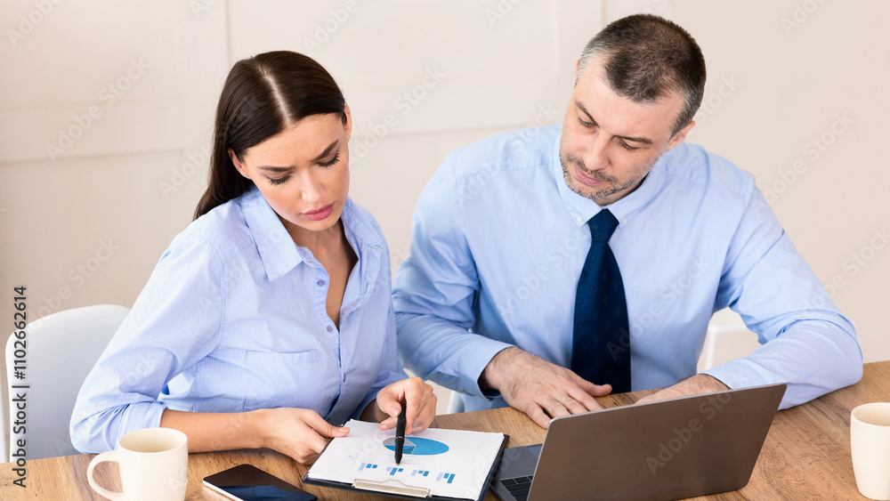 Fototapeta premium Business Partnership. Two Coworkers Working Together Using Laptop And Charts Sitting At Desk In Modern Office.