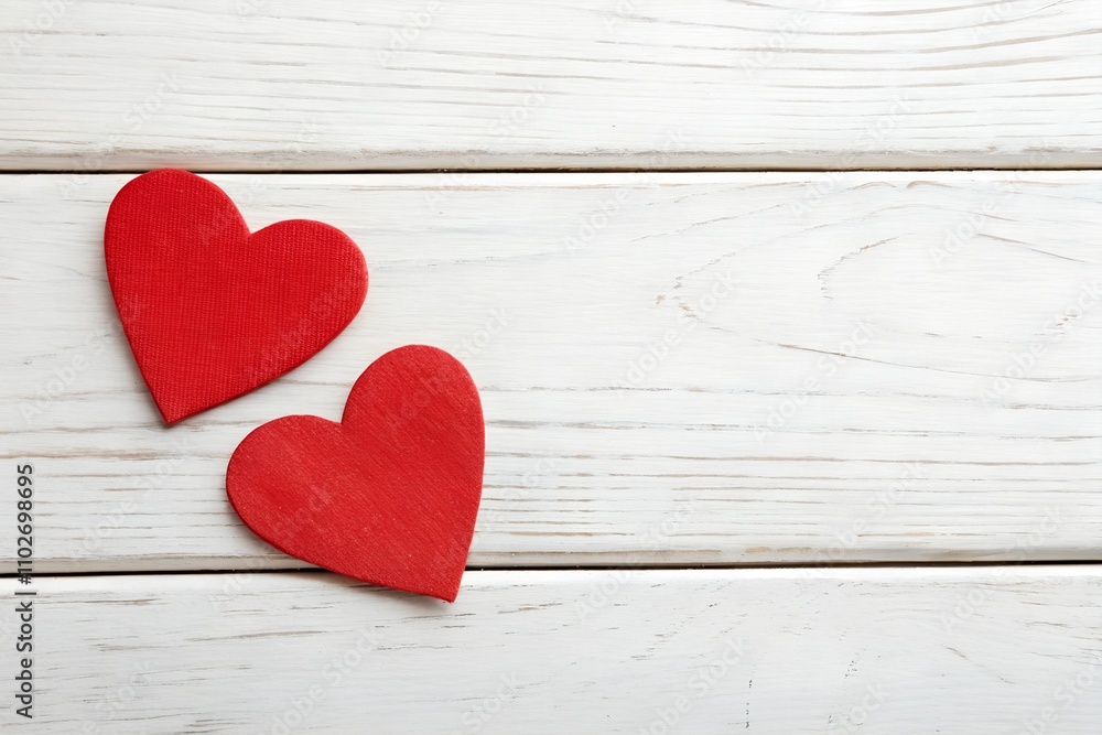 Two red heart shapes placed on a white wooden background, symbolizing love and togetherness. The rustic texture adds charm, creating a romantic and serene atmosphere. Two red heart shapes placed on a white wooden background, symbolizing love and togetherness. The rustic texture adds charm, creating a romantic and serene atmosphere.