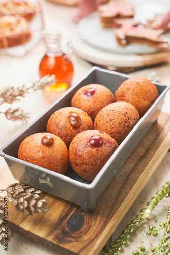 Traditional Colombian buñuelos served in a metal baking tray, resting on a wooden board. These golden, crispy cheese fritters are beautifully decorated with dulce de leche and fruit jam fillings