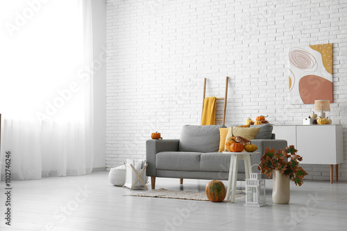 Interior of light living room with autumn decor, sofa and table photo