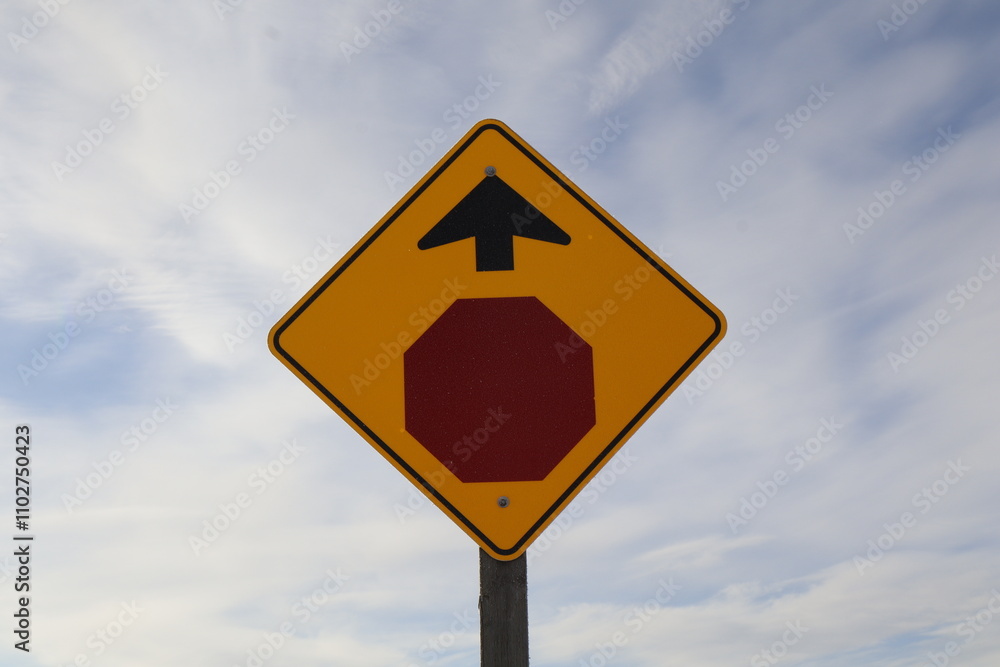 A diamond shaped yellow sign, indicating there is a stop sign up ahead. A diamond shaped yellow sign, indicating there is a stop sign up ahead.