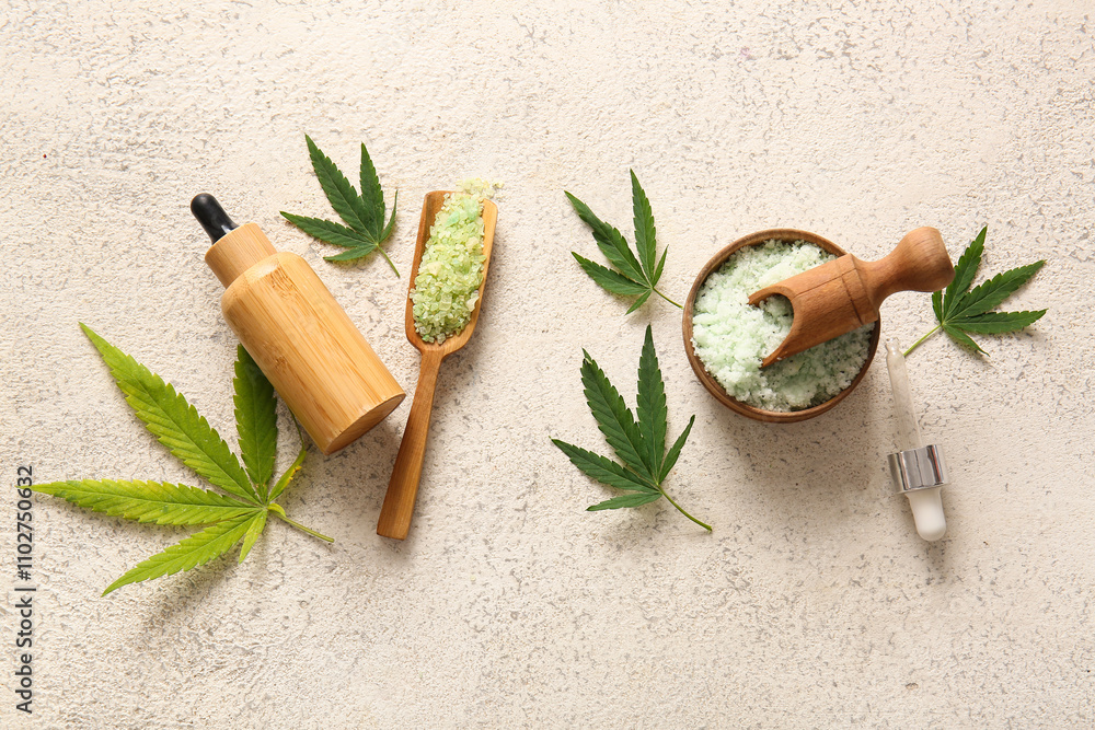 Bottle of hemp cosmetic oil with sea salt and leaves on white background