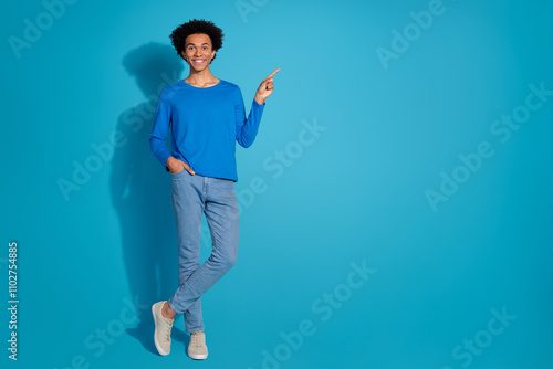 Full size photo of pretty young male point empty space wear trendy outfit isolated on blue color background photo