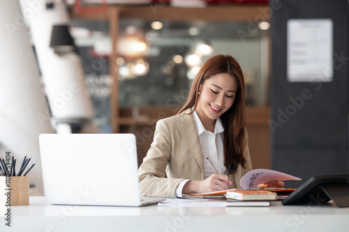 Young asian businesswoman working in her office, using paperwork and laptop