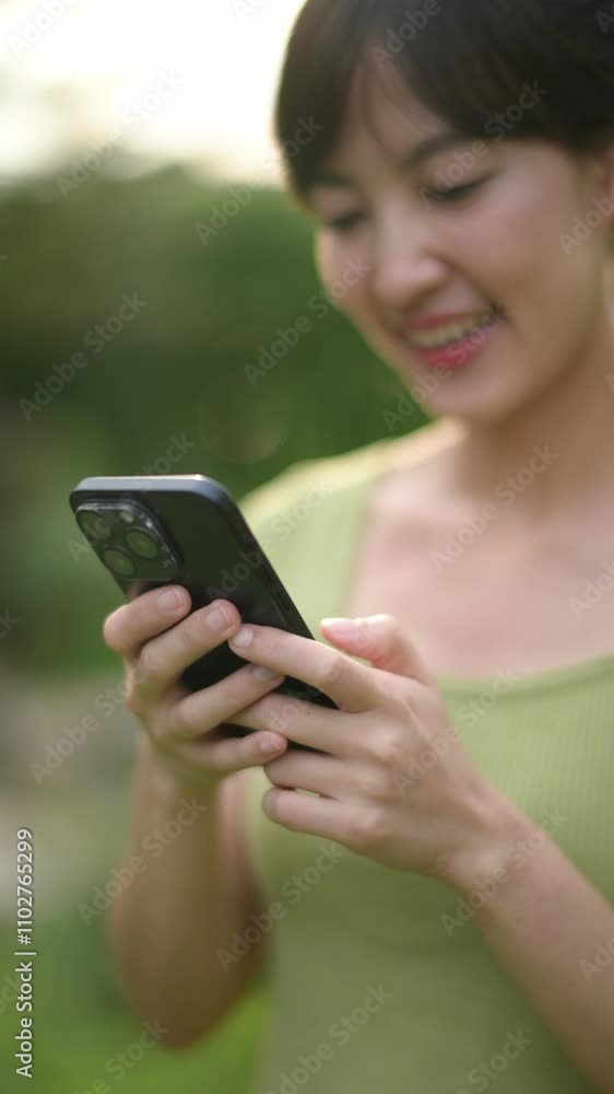 Vertical video of Smiling Woman Using Smartphone Outdoors in Greenery Vertical video of Smiling Woman Using Smartphone Outdoors in Greenery