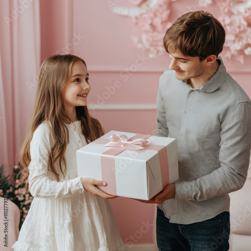 joyful girl receives large gift box from smiling man in pink themed room. moment captures happiness and surprise, perfect for celebrations