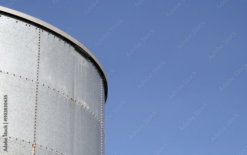 Large metal storage water tank against a clear blue sky abstract Large metal storage water tank against a clear blue sky abstract