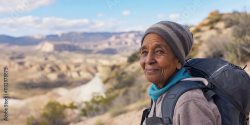 Elderly African American female hiker with backpack smiling in desert landscape