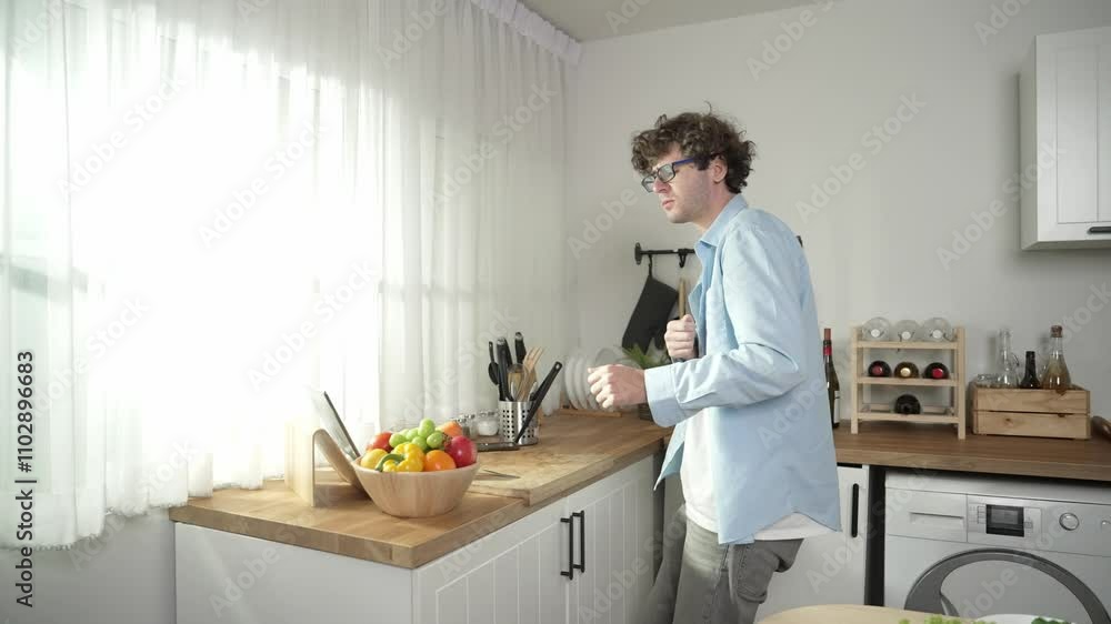 Happy father move to music while cooking food and prepare lunch at modern kitchen. Active dad dancing to song while making healthy food or salad surrounded with vegetable and kitchenware. Pedagogy. Happy father move to music while cooking food and prepare lunch at modern kitchen. Active dad dancing to song while making healthy food or salad surrounded with vegetable and kitchenware. Pedagogy.