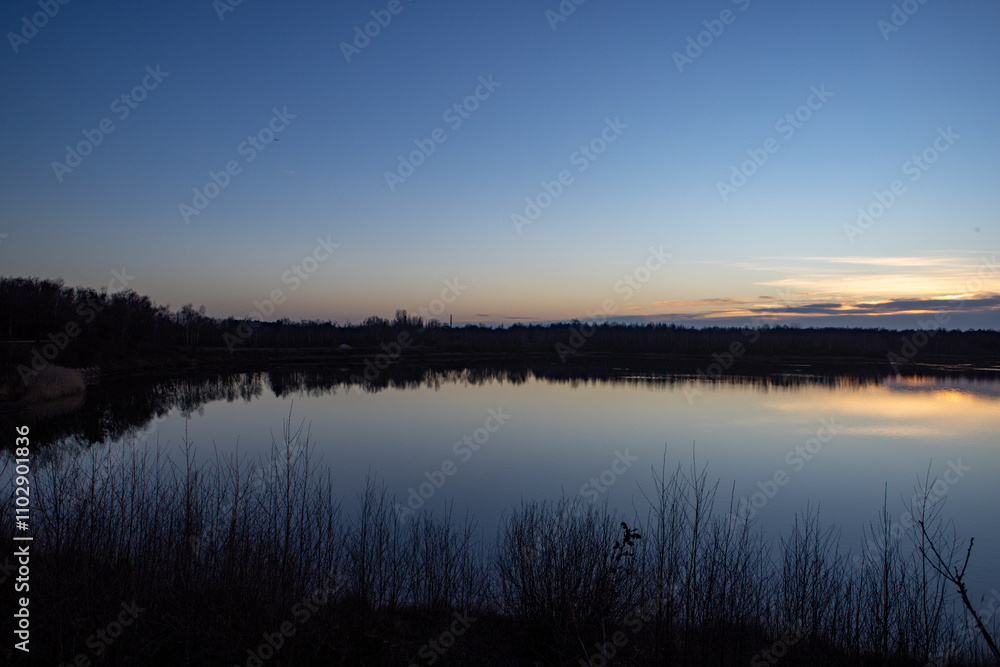 A beautifully serene dusk view reflected on a perfectly still lake, completely surrounded by natures tranquility